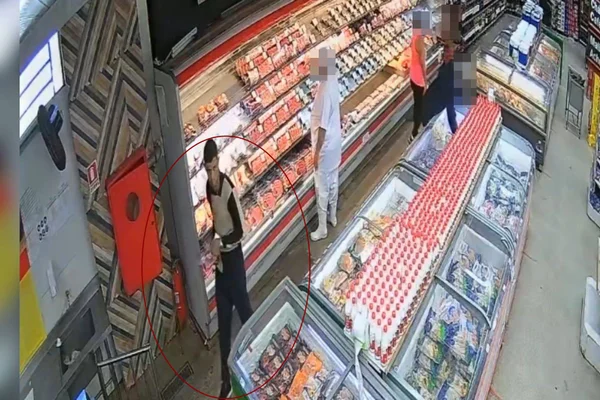 Imagem colorida de um homem com um pedaço de carne na mão dentro de um mercado - Metrópoles