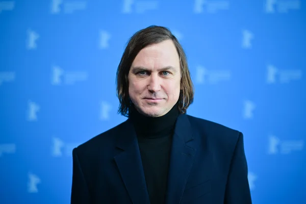 Imagem colorida do ator Lars Eidinger posando para fotos em tapete vermelho - Metrópoles