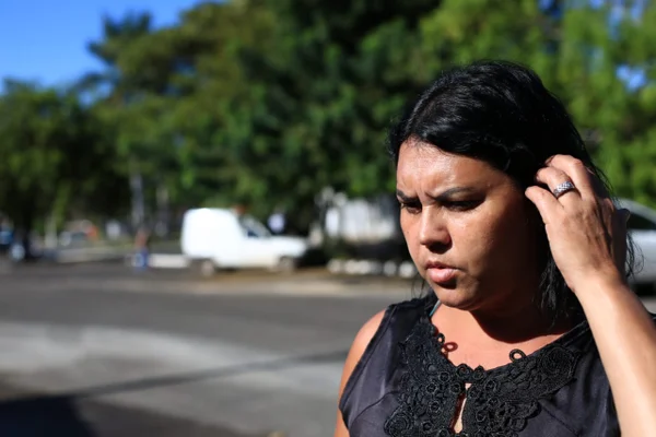 Mãe de adolescente espancado diz que quer justiça. Mulher com blusa preta pegando no cabelo