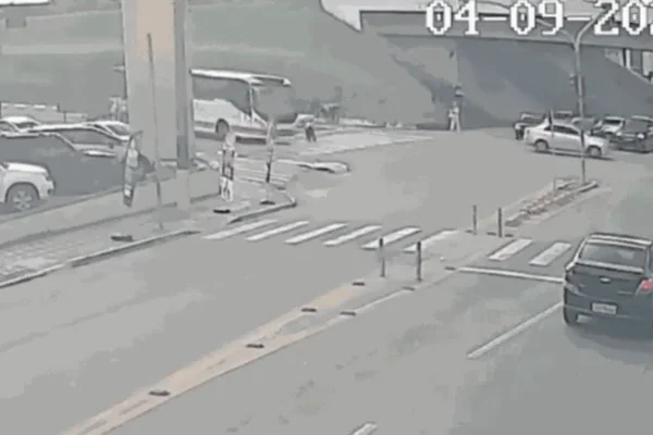 Imagem colorida de idoso tropeçando em avenida e sendo atropelado por ônibus - Metrópoles