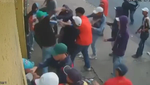 Em foto colorida bando rouba jovem encostado em parede de calçada - Metrópoles
