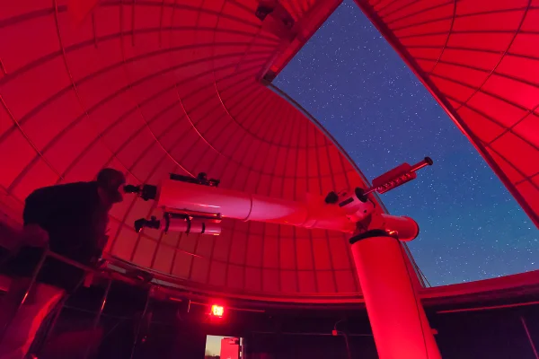 Dentro do observatório, um astrônomo realiza observações com um grande telescópio refrator no campus de astronomia 3RF, no Texas. Metrópoles