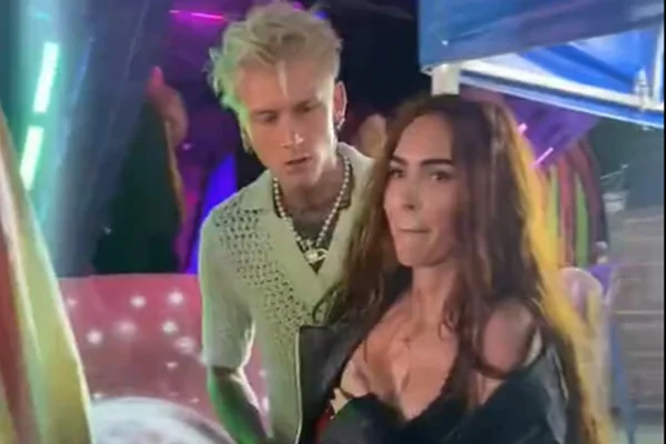 Print de um vídeo mostra Machine Gun Kelly e Megan Fox em um evento. Ele está com uma camiseta clara, enquanto a atriz está de preto - Metrópoles