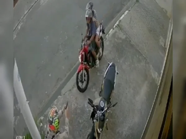 Imagem de homem de capacete apontando arma para dois homens em uma moto; policial penal atirou em dois bandidos, matando um e ferindo o outro - Metrópoles