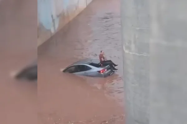 Imagem colorida mostra homem ilhado em cima de carro durante fortes chuvas em Goiânia - Metrópoles