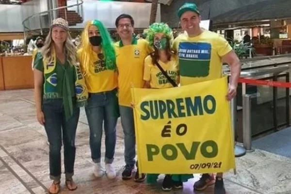 Grupo de pessoas vestidas de verde e amarelo com faixa contra o STF