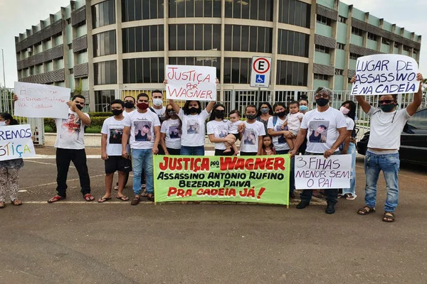 pessoas seguram cartazes e faixa