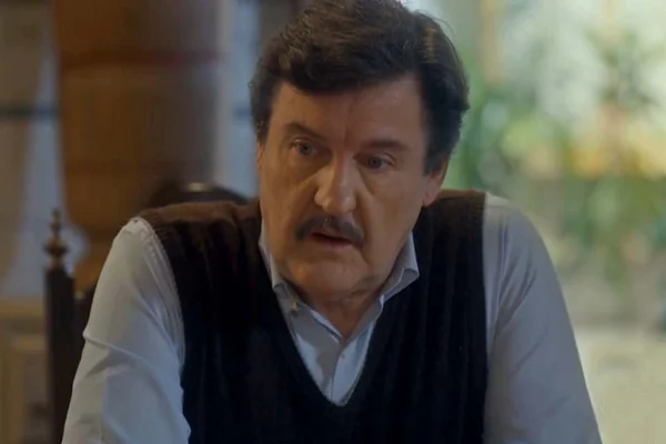 Foto de um homem branco, com cabelo preto e rugas no rosto. Ele usa um suéter e uma blusa azul por baixo - Metrópoles