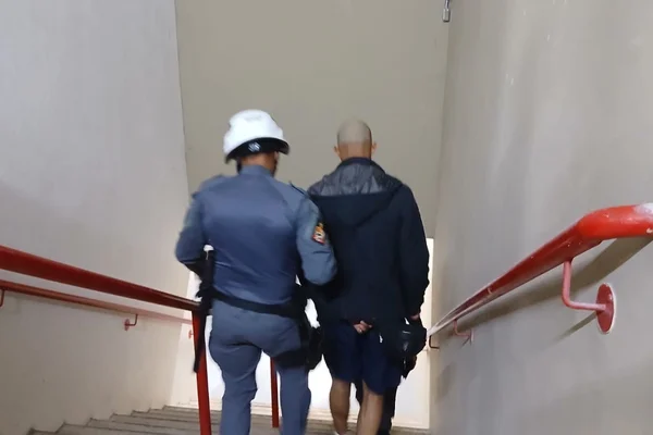 Imagem colorida de policial prendendo foragido da Justiça em estádio de SP - Metrópoles