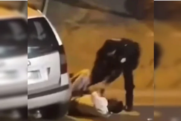 Homem caído de branco luta contra policial