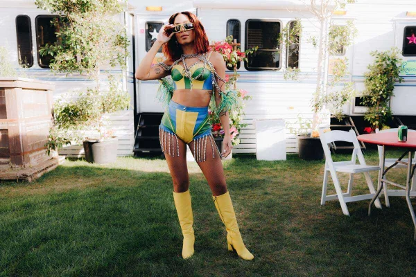 Na imagem com cor, Anitta posa em frente a trailer branco