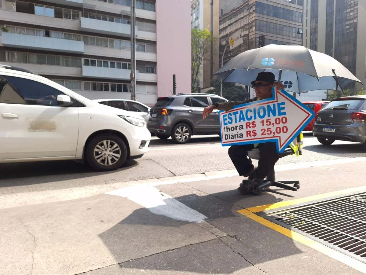 Homem-placa de estacionamento se protege do sol na Avenida Paulista com guarda-sol