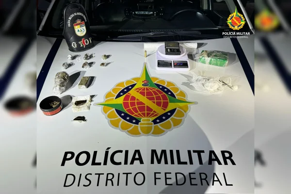 Imagem colorida de porções de drogas diversas e uma balança de precisão sobre uma viatura da PMDF