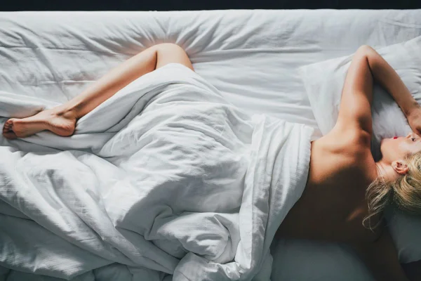 foto colorida de um mulher branca deitada na cama sozinha