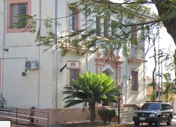 Imagem colorida de delegacia com viatura estacionada em frente à entrada do prédio - Metrópoles