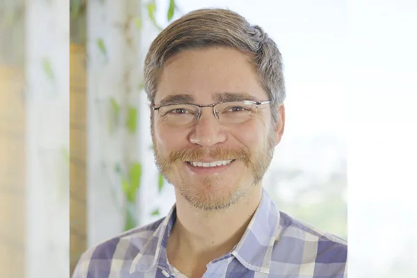 Foto colorida de homem de barba sorrindo - Metrópoles