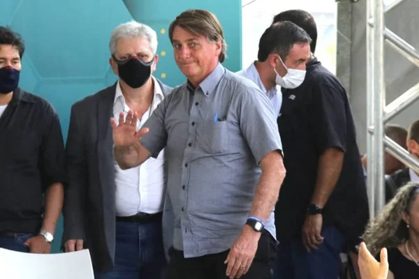 Bolsonaro em evento de inauguração do Córrego Ipiranga, em São Paulo. Ele aparece sem máscara, dando um gesto de cumprimento, de camisa social - Metrópoles