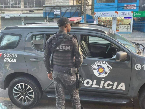 Foto colorida mostra policial militar da Rocam parado em frente a viatura