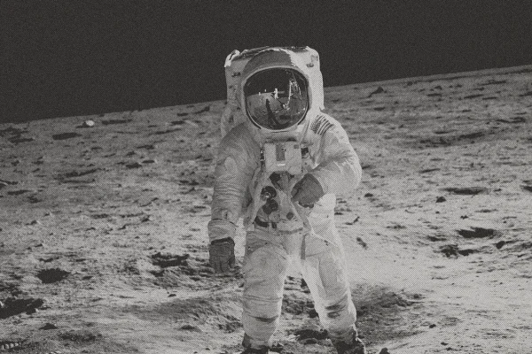 Astronauta caminhando na Lua em tom preto e branco. Metrópoles