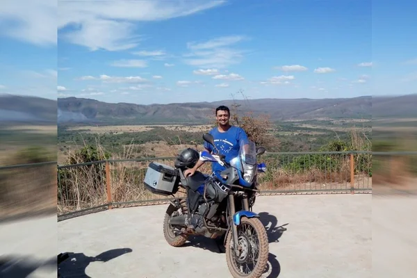 Homem posa ao lado de moto