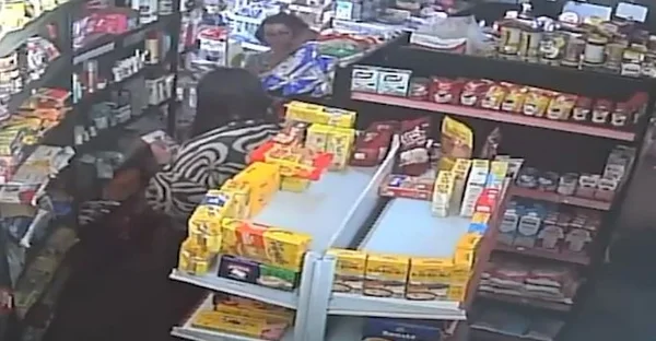 Imagem colorida mostra uma mulher com um bebê no colo conversando com um homem de cabelos compridos em uma mercearia - Metrópoles