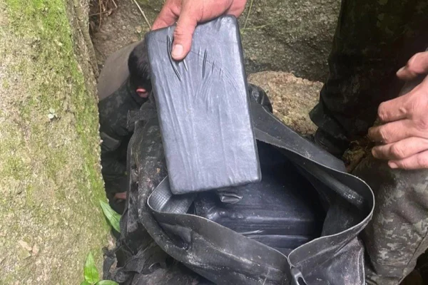 Imagem colorida de tijolos de drogas embalados com plástico preto dentro de saco - Metrópoles