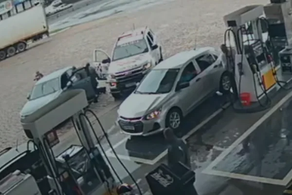Imagem colorida de viatura policial abordando suspeitos em posto de gasolina. Metrópoles