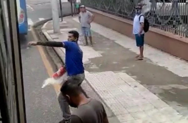 print de vídeo que mostra um motorista de ônibus arremessando um extintor