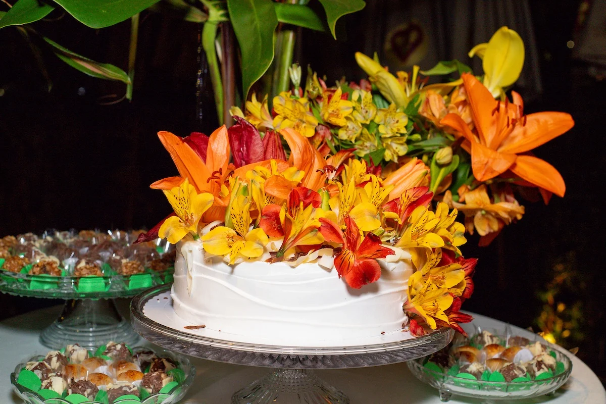 Bolo de aniversário com adornos floridos coloriu a mesa dos doces Bolo de aniversário com adornos floridos coloriu a mesa dos doces