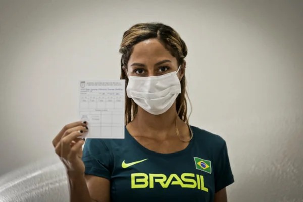 atleta segura carteira de vacinação