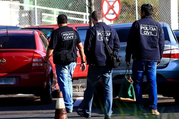 Três agentes da PCDF, de costas, caminhando