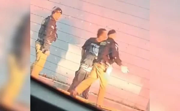 Fotografia colorida, policiais agredindo morardor de rua