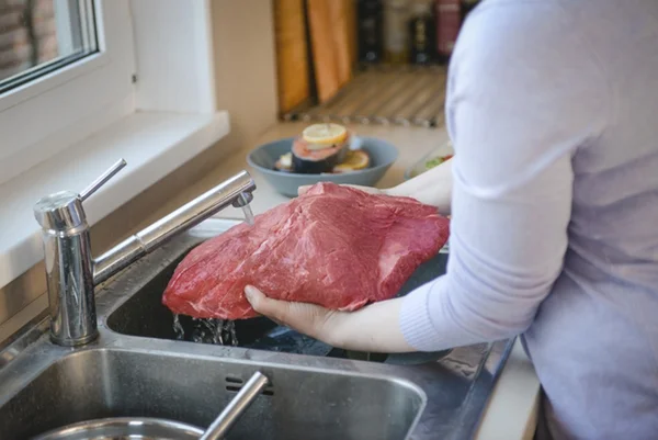 Mulher lavando carne - Metrópoles