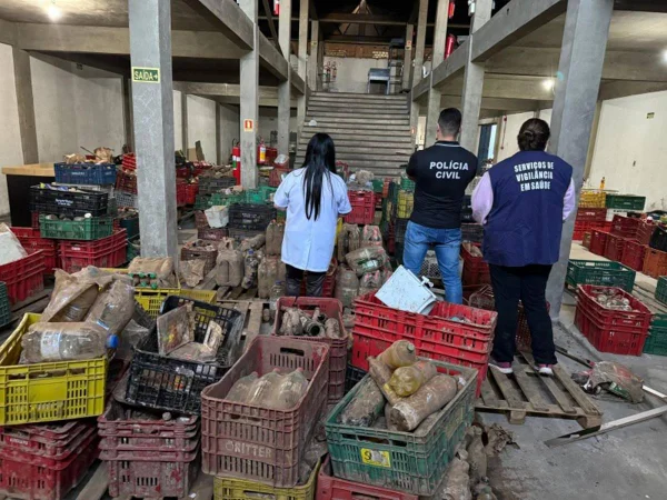Imagem colorida mostra pessoas de costas em um estoque de supermercado - Metrópoles