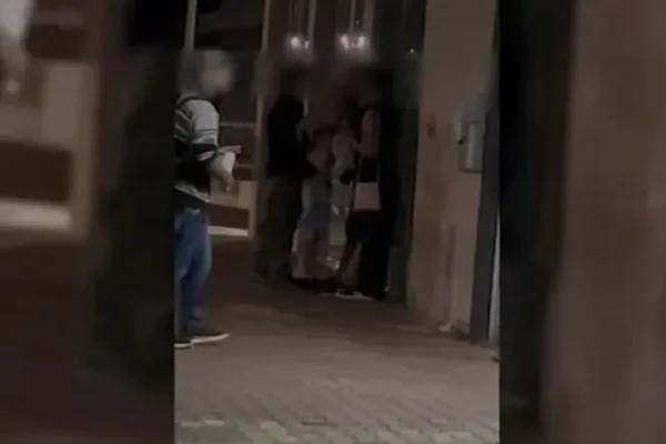 Pessoas paradas em beco escuro em Cascavel, Paraná.