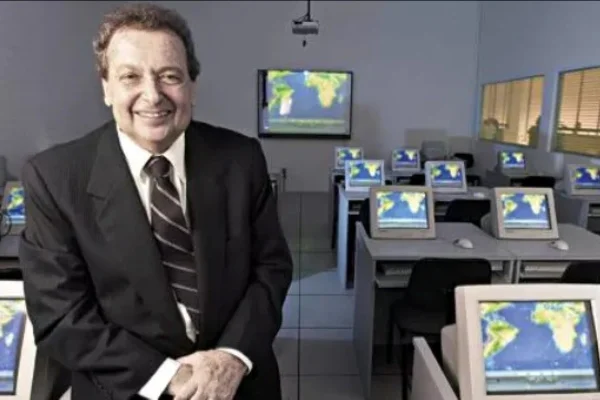 Foto de João Carlos Di Genio, um homem branco de cabelos castanhos, sentado em mesa ao lado de computadores - Metrópoles