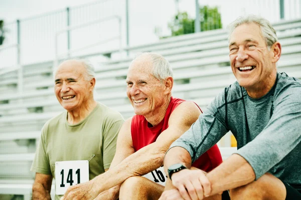 Atletas masculinos seniores sorrindo e rindo juntos nas arquibancadas