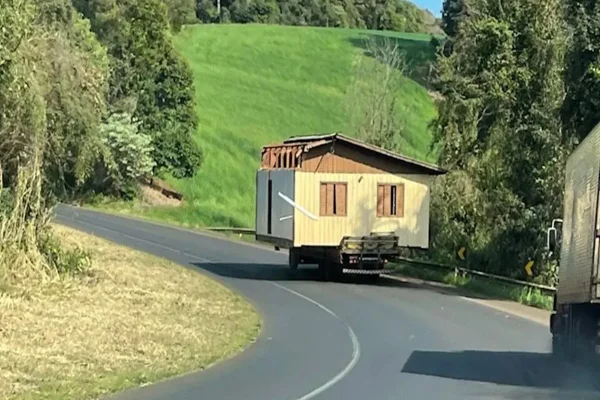 Imagem colorida de casa sendo transportada por caminhão - Metrópoles