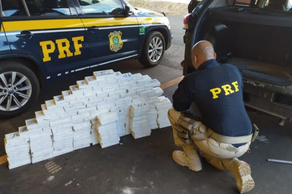 Imagem colorida mostra agente da Polícia Rodoviária Federal diante de carga de 187 celulares apreendidos com homem em rodovia no interior de São Paulo - Metrópoles