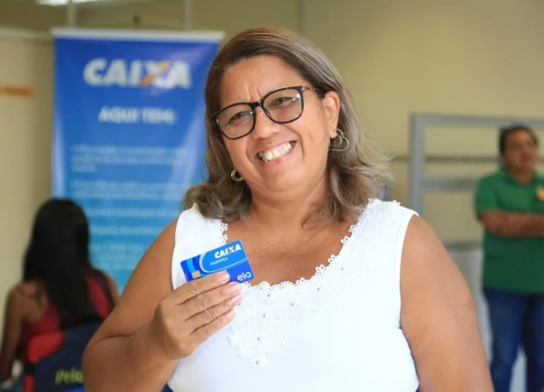 Imagem colorida de mulher segurando um cartão do Banco Caixa Econômica - Metrópoles