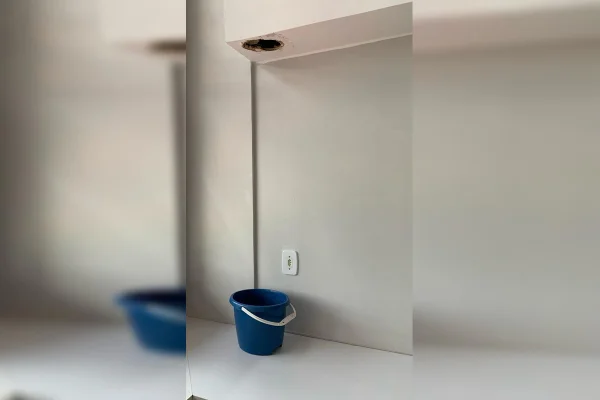 Foto de buraco no teto com balde embaixo para amparar na chuva