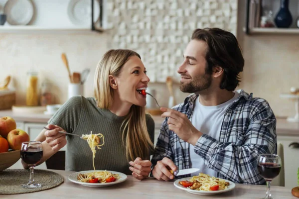 Casal comendo macarrão e dando um ao outro