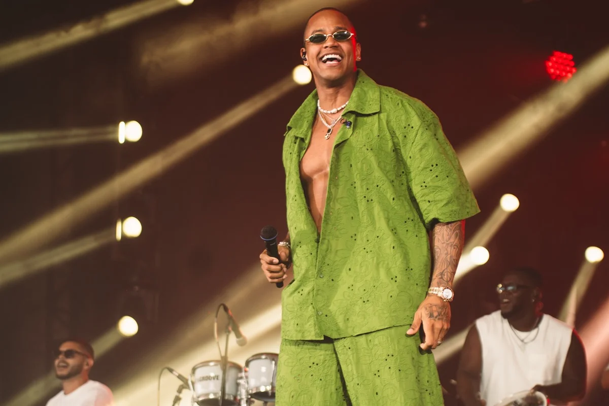 Foto de Léo Santana sorridente no palco com um look verde - Metrópoles