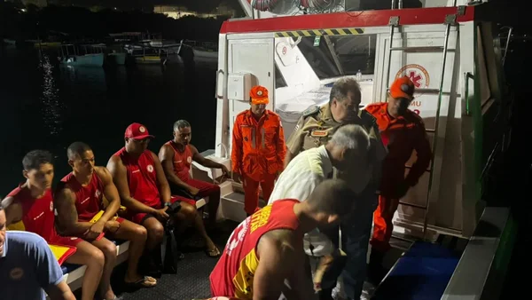 Imagem de militares do corpo de bombeiros tentando resgatar as vítimas do naufrágio, em cima de um barco da corporação, a noite - Metrópoles