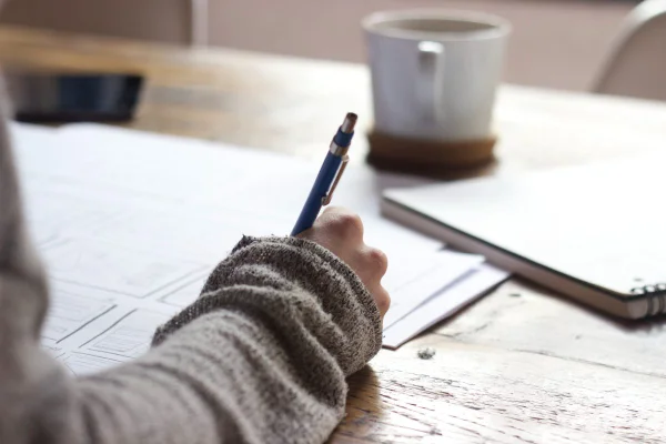 Braço de uma pessoa fazendo anotações em um caderno