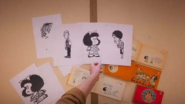 Foto colorida de uma mesa com vários desenhos da Mafalda - Metrópoles