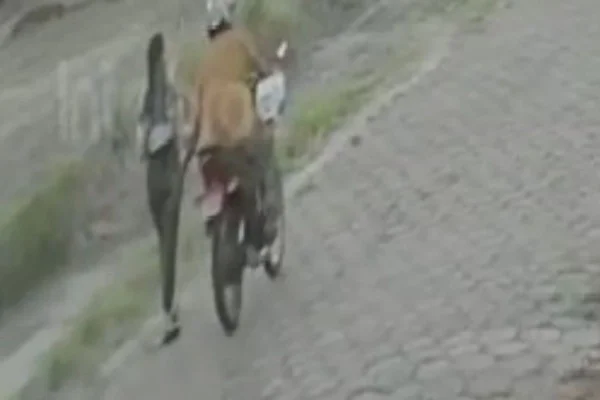 Imagem colorida mostra motociclista dando tapa na bunda de uma mulher que andava com bebê no colo - Metrópoles