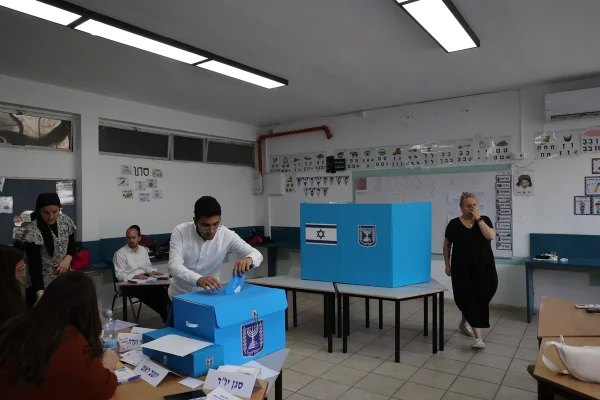 Um homem judeu ultraortodoxo deposita seu voto, enquanto outros aguardam para votar em uma escola que serve como local de votação durante as eleições legislativas de Israel, em Bnei Brak