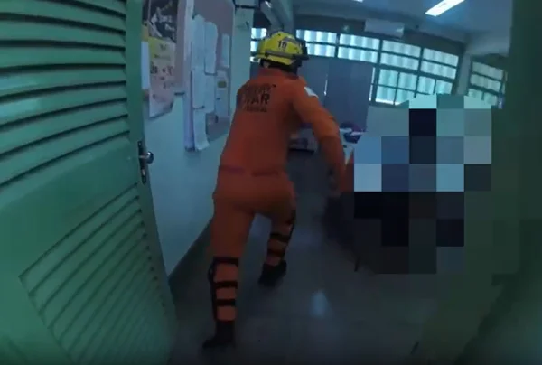 Imagem colorida de um bombeiro correndo em uma sala de aula de porta verde