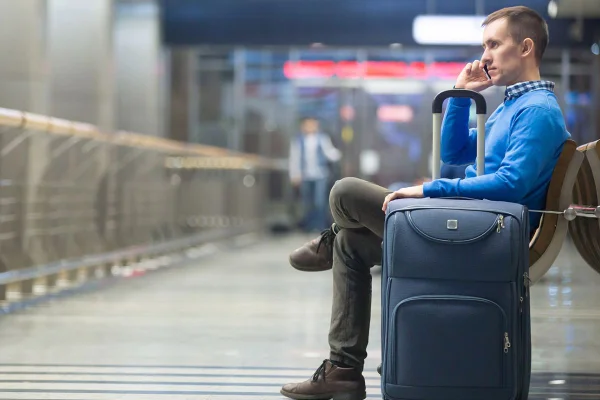 homem em aeroporto ao lado de uma mala